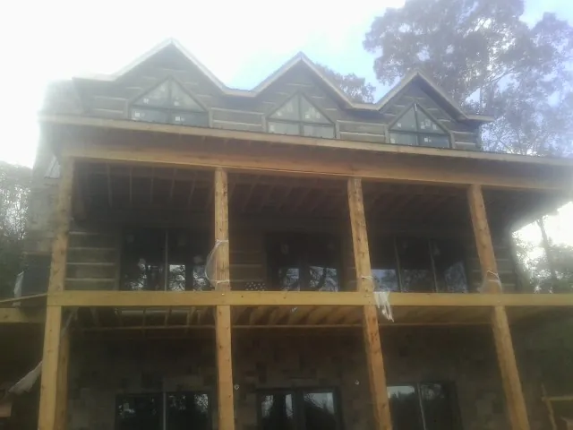 Dormers and porch framing on a large log home under construction — Roof Coating work by our crew in Dutton