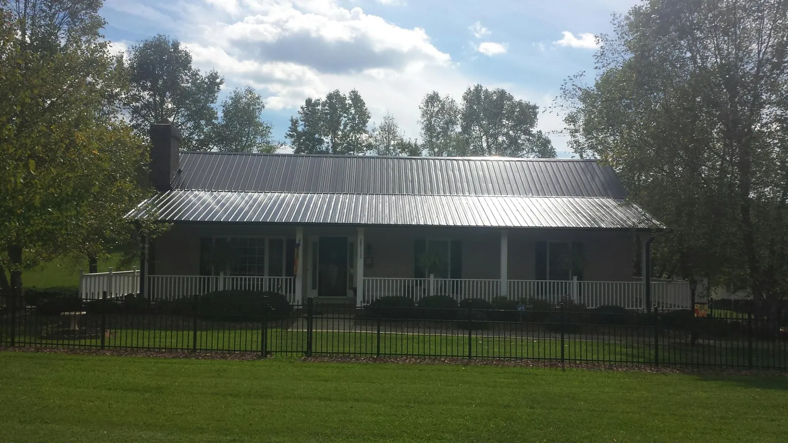 Gray metal roof on a brick ranch with a full width front porch — Gutter Guard Installation work by our crew in Dutton
