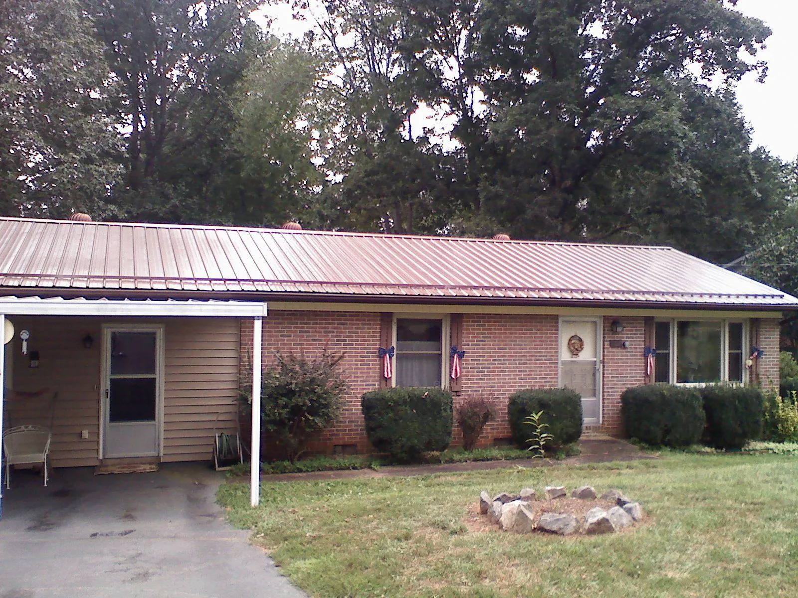Bronze metal roof and carport on a brick ranch home — Roof Repair work by our crew in Dutton