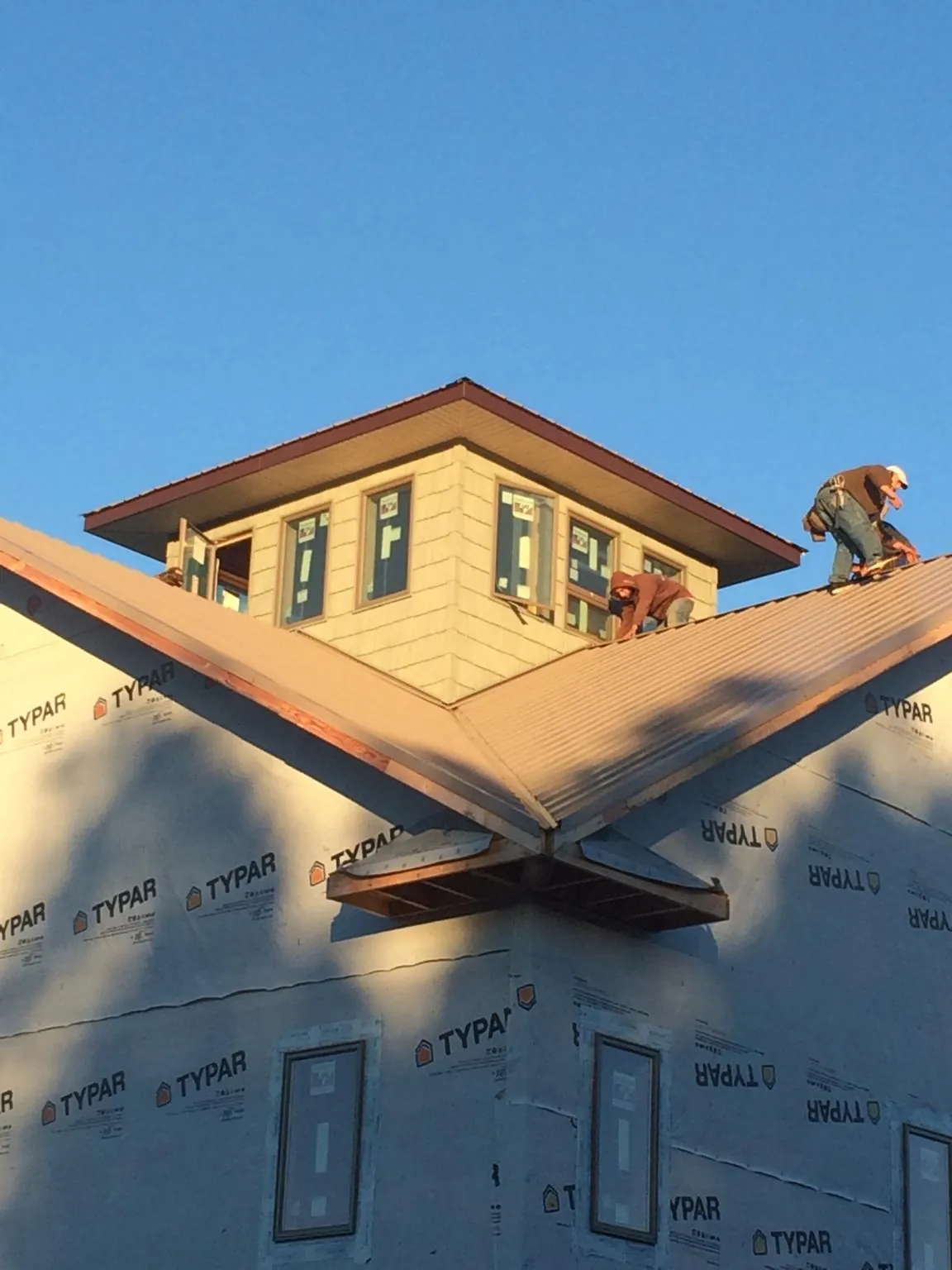 Roofers working around a rooftop cupola on a new metal roof at sunset — Roof Waterproofing in Dutton by Roofing Brothers